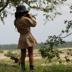 little girl on safari looking through binoculars across the Tanzanian landscape